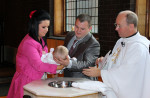 Proud Parents With Child At The Font At A Christening In Church